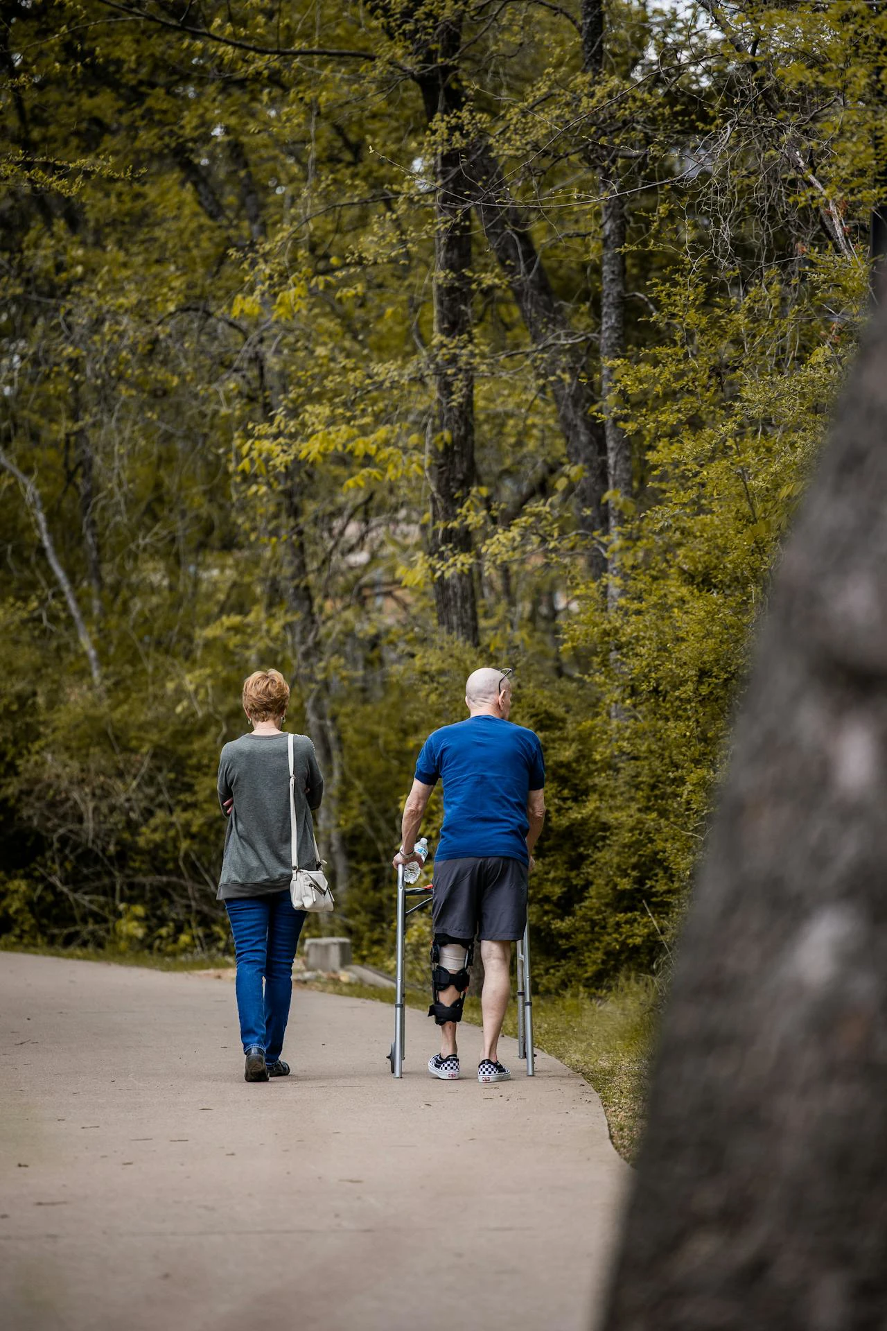 Vrouw en man met knie orthese en krukken wandelen in bos